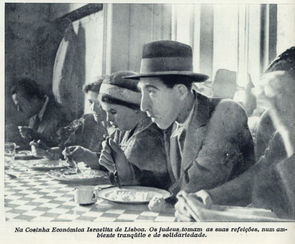 A photo of several people eating simple food on a table with a checkerboard pattern. The main subject is a young man with a wide-brimmed hat.