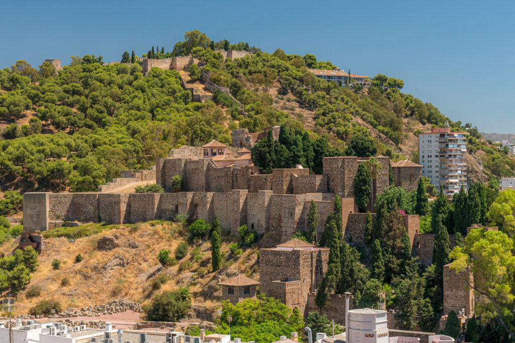A castle's walls dramatically zig-zag up a mountainside.